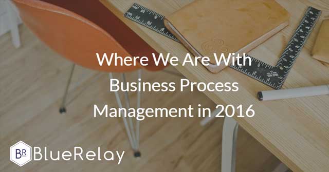 Image of a light brown wooden desk with an orange chair. On top of the table is a brown leather notebook and a black right angle ruler
