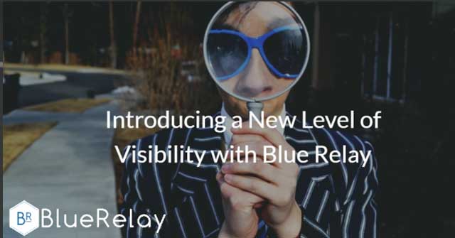 Image of a man with light blue framed sunglasses, wearing a dark pinstripe suit, holding a magnifying glass against his face, enlarging his nose and eye area